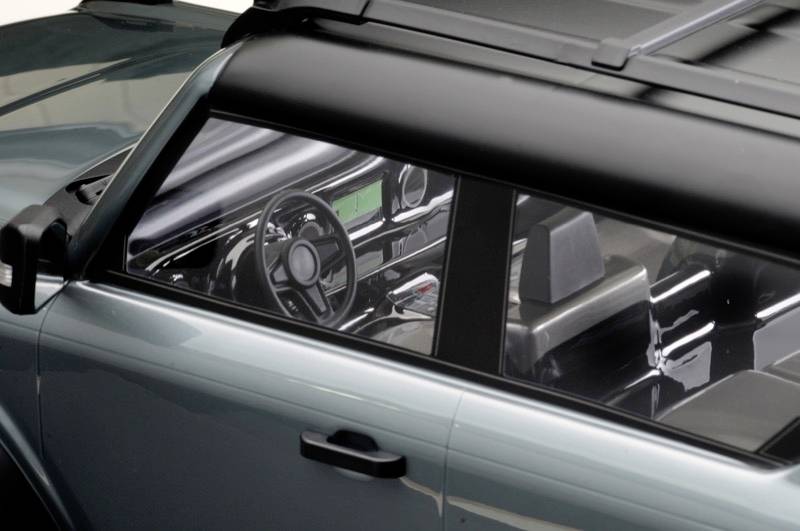 View of a classic car through the window, showing the steering wheel and dashboard. The vehicle has a dark bodywork.