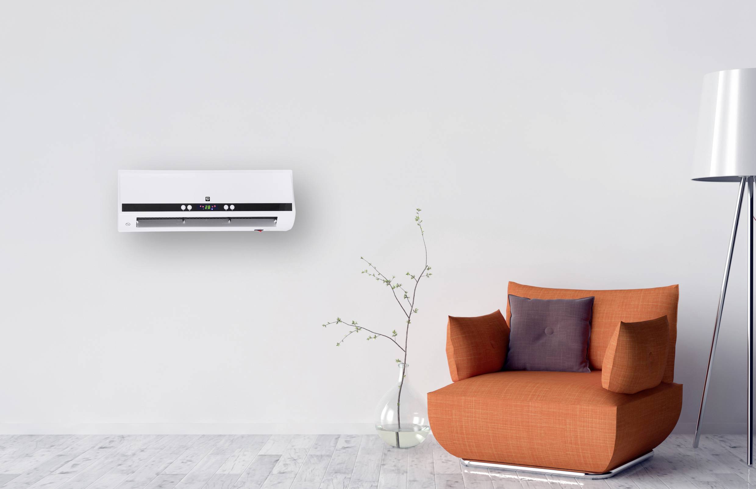 A white air conditioning unit hangs on a white wall above a modern, orange armchair and a vase with branches.