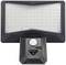 A rectangular LED outdoor floodlight with many small, visible LEDs. Below is a motion sensor above a control panel.