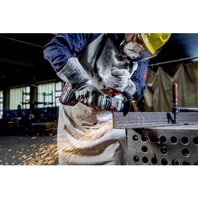 A tradesman is wearing protective clothing and using an angle grinder to generate sparks while working on a piece of metal in a workshop.