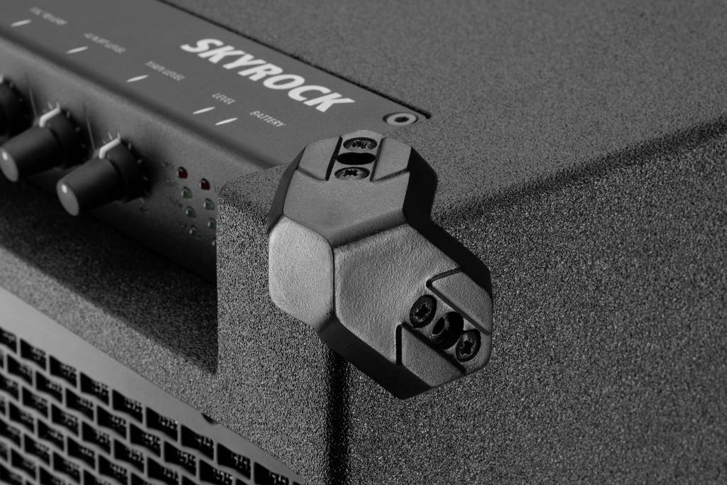 Close-up of a 'Skyrock' amplifier, with a microphone stand on the right side. Three-button control panel and ventilation grille visible.