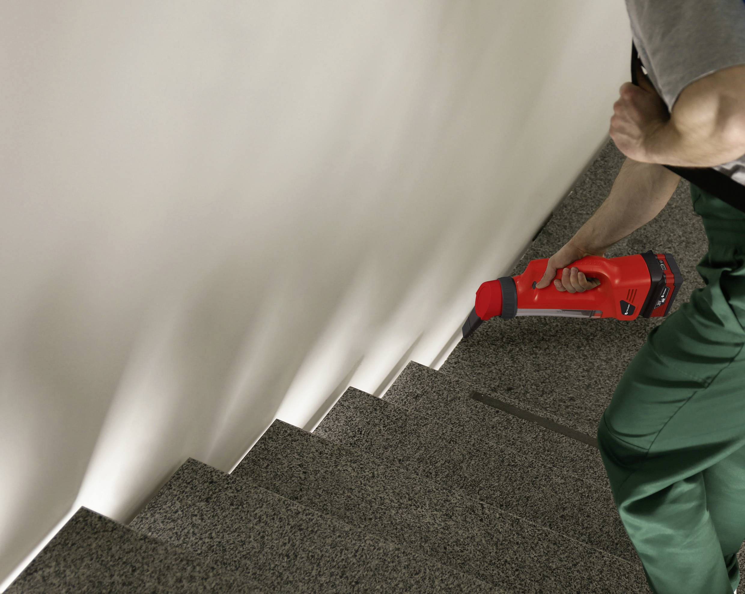 A person is cleaning a staircase with a red handheld vacuum cleaner. Focused on the cleaning process in what appears to be a domestic setting.