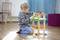 A little boy plays intently on a wooden floor with a colourful toy tool set.