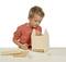 A boy in a red shirt is building a wooden birdhouse against a white background. Tools and wooden parts are laid out on the table.