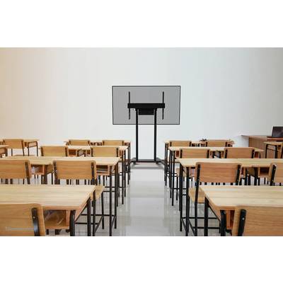 Classroom with empty wooden desks and chairs. A large screen at the front. Walls on the left and right, and a teacher's desk are visible.