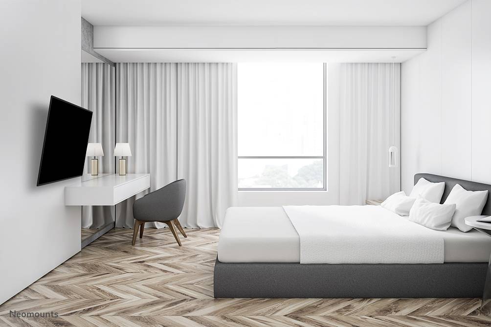 Modern bedroom with a large bed, a desk and a chair. A window lets in plenty of natural light.