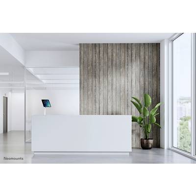 Reception area with a white counter, green potted plant and a wall with wooden panelling. A tablet is positioned on the left side of the counter.