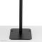 A black metal stand with a rectangular base and vertical rod, standing on a flat, grey surface.