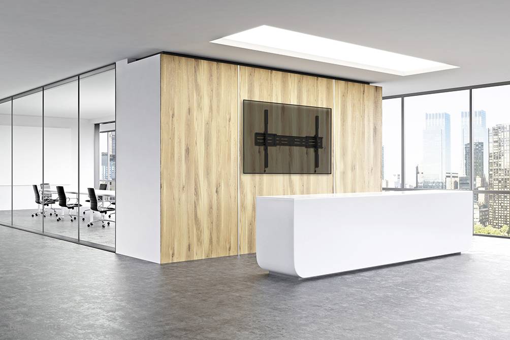 A modern, minimalist office space with a white reception desk, glass walls, and a wooden panel with a TV mount.