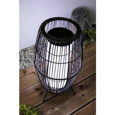 A contemporary floor lamp with a black wire frame illuminates wooden decking. White pebbles are scattered in the background.