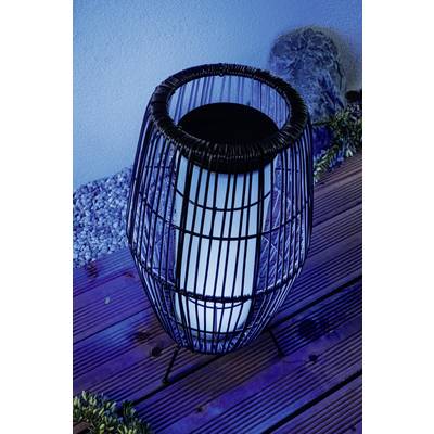 A modern outdoor lantern with a black metal cage and blue backlighting on a wooden terrace, surrounded by pebbles.