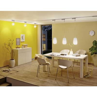 A modern dining room with yellow walls, a white table, chairs and hanging lamps. The window reveals the twilight.