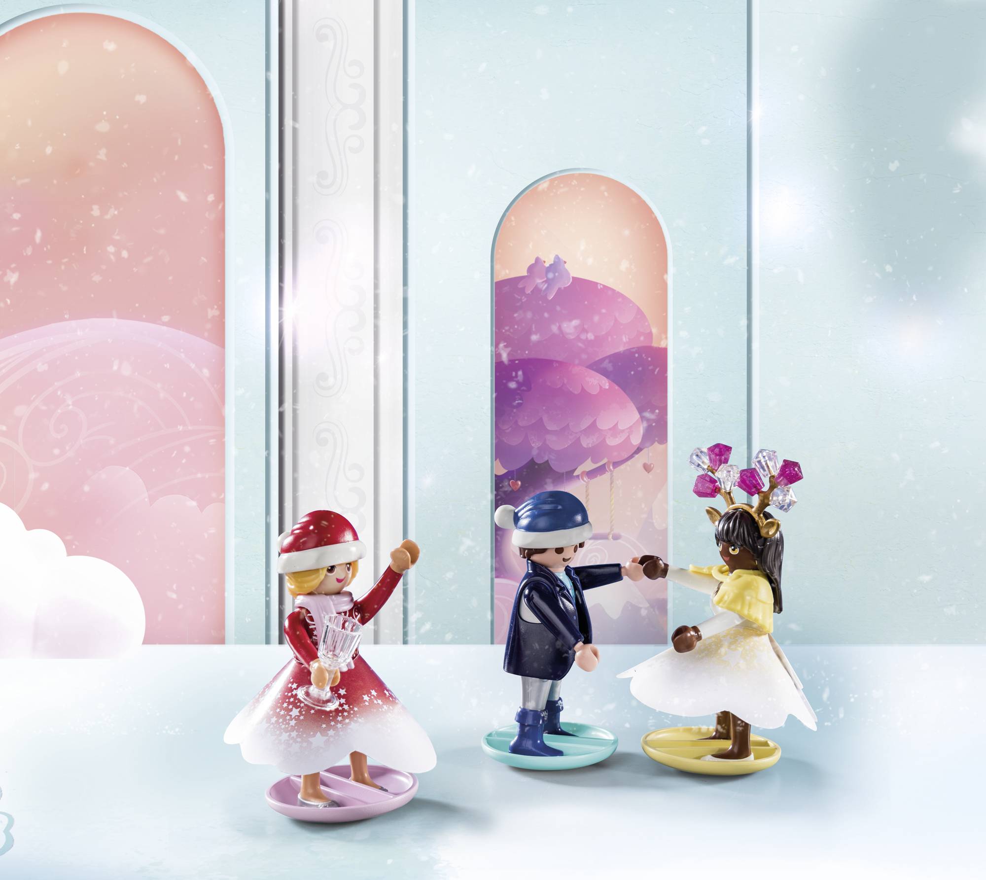 Three Playmobil figures in winter clothing are dancing in a fairytale-like room with snow-covered trees in the background.