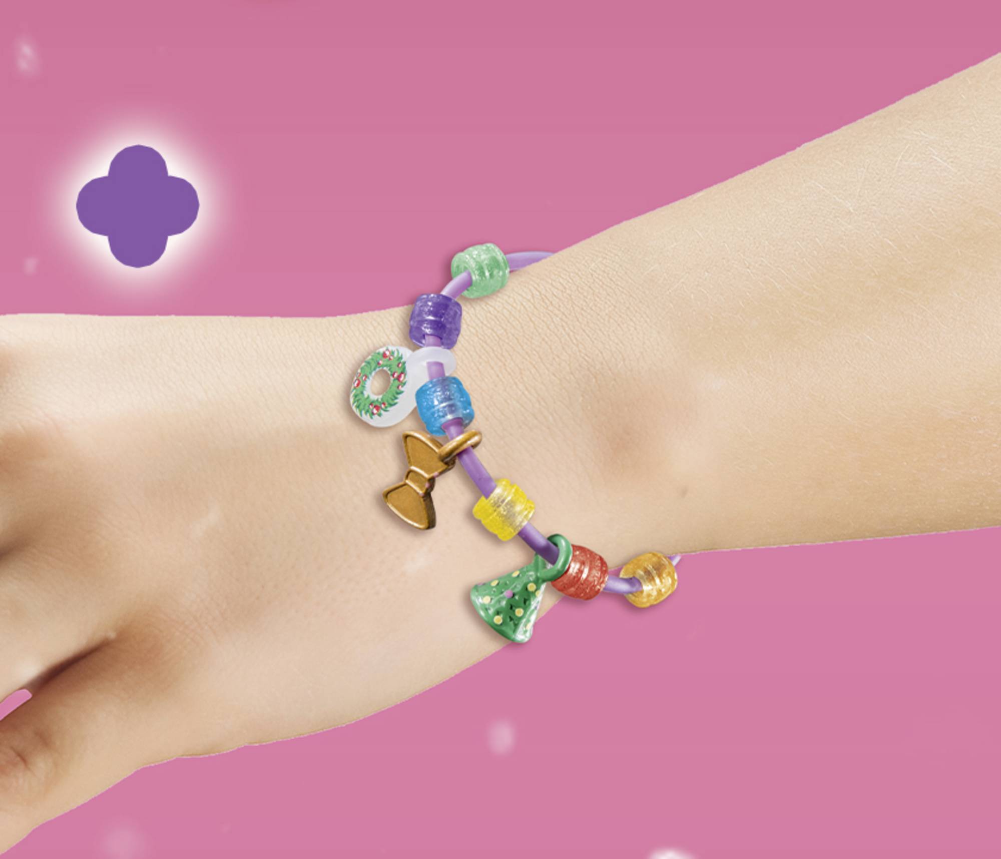 A hand is wearing a colourful bracelet with various charms on a pink background.