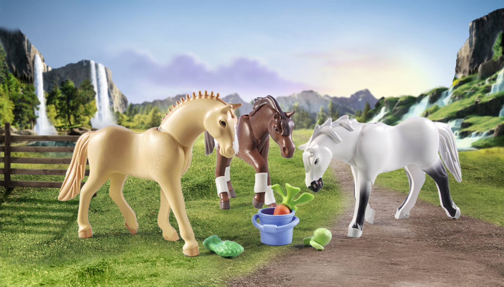 Three toy horses on a meadow with a bucket full of vegetables. The background shows mountains and waterfalls.