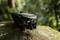 A compact, folded drone lies on a moss-covered rock in a wooded area.