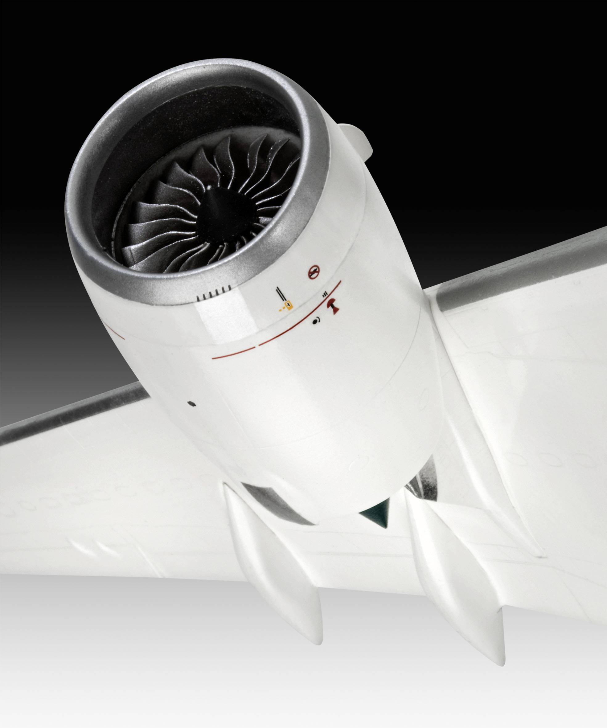 A close-up of an aircraft engine beneath the wing of an aeroplane, highlighted against a black background.