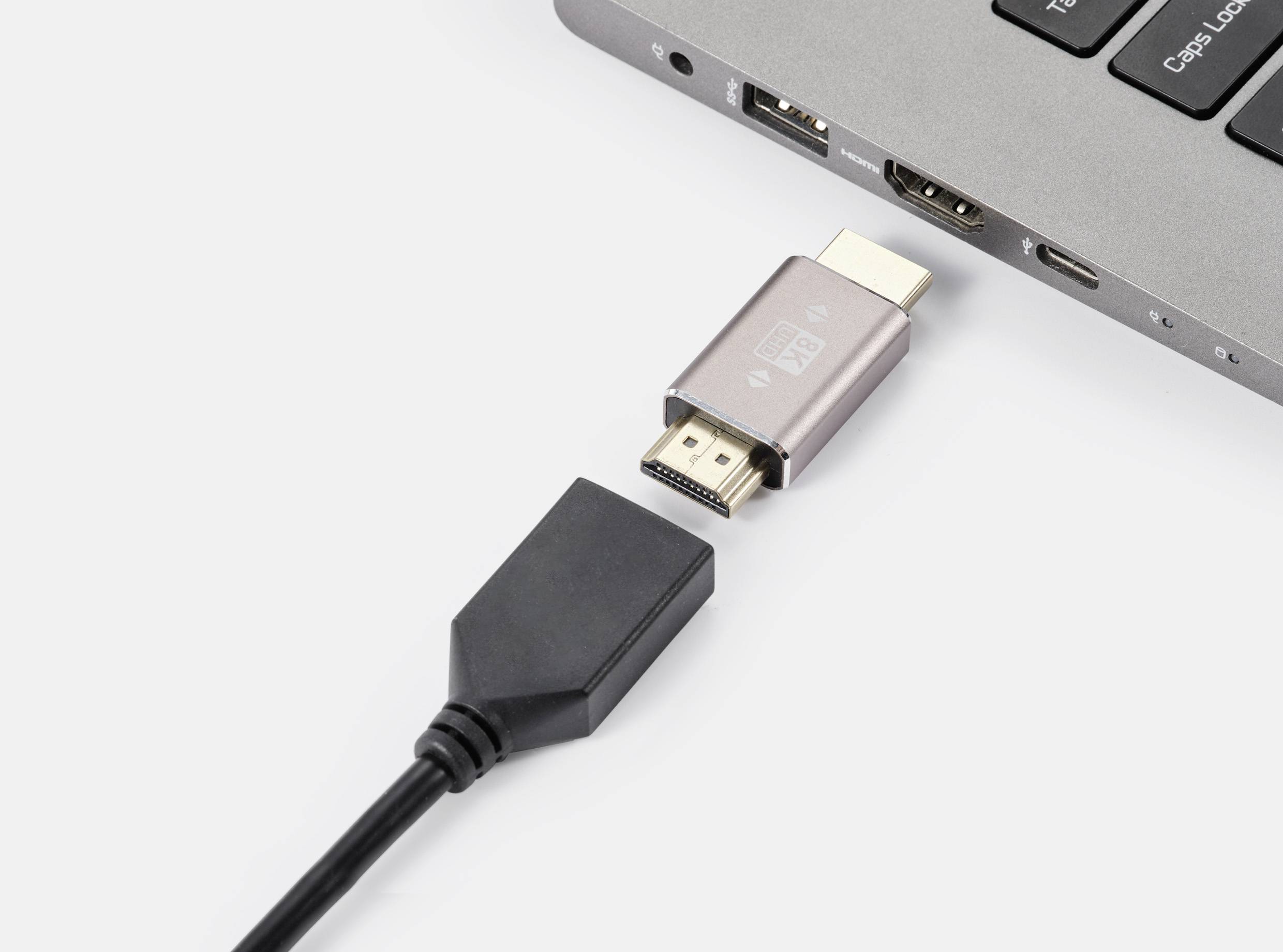 An HDMI cable is connected to an adapter plugged into a laptop.
