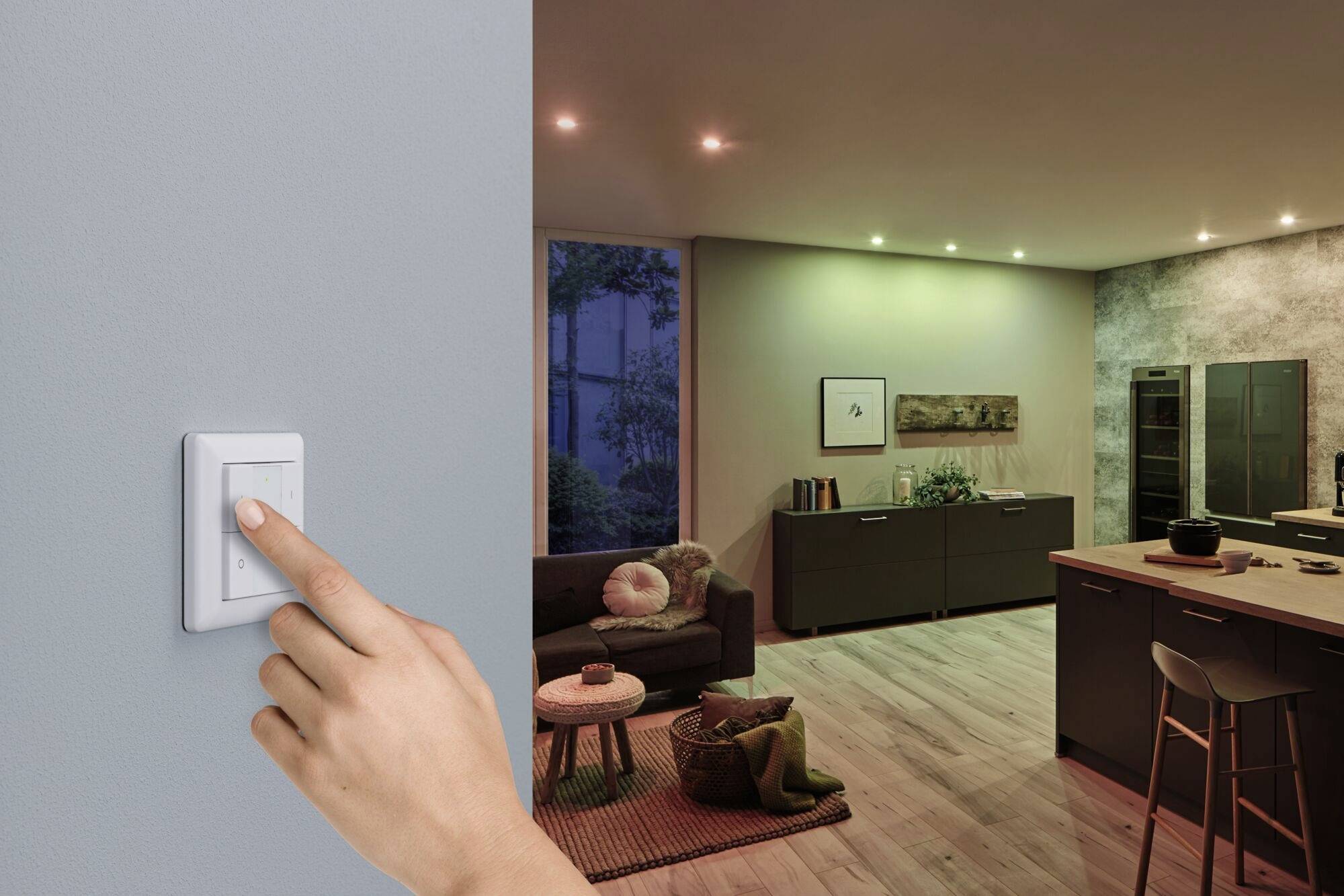 A hand operates a light switch on the wall to turn on a modern-furnished living room with dimmed lighting.