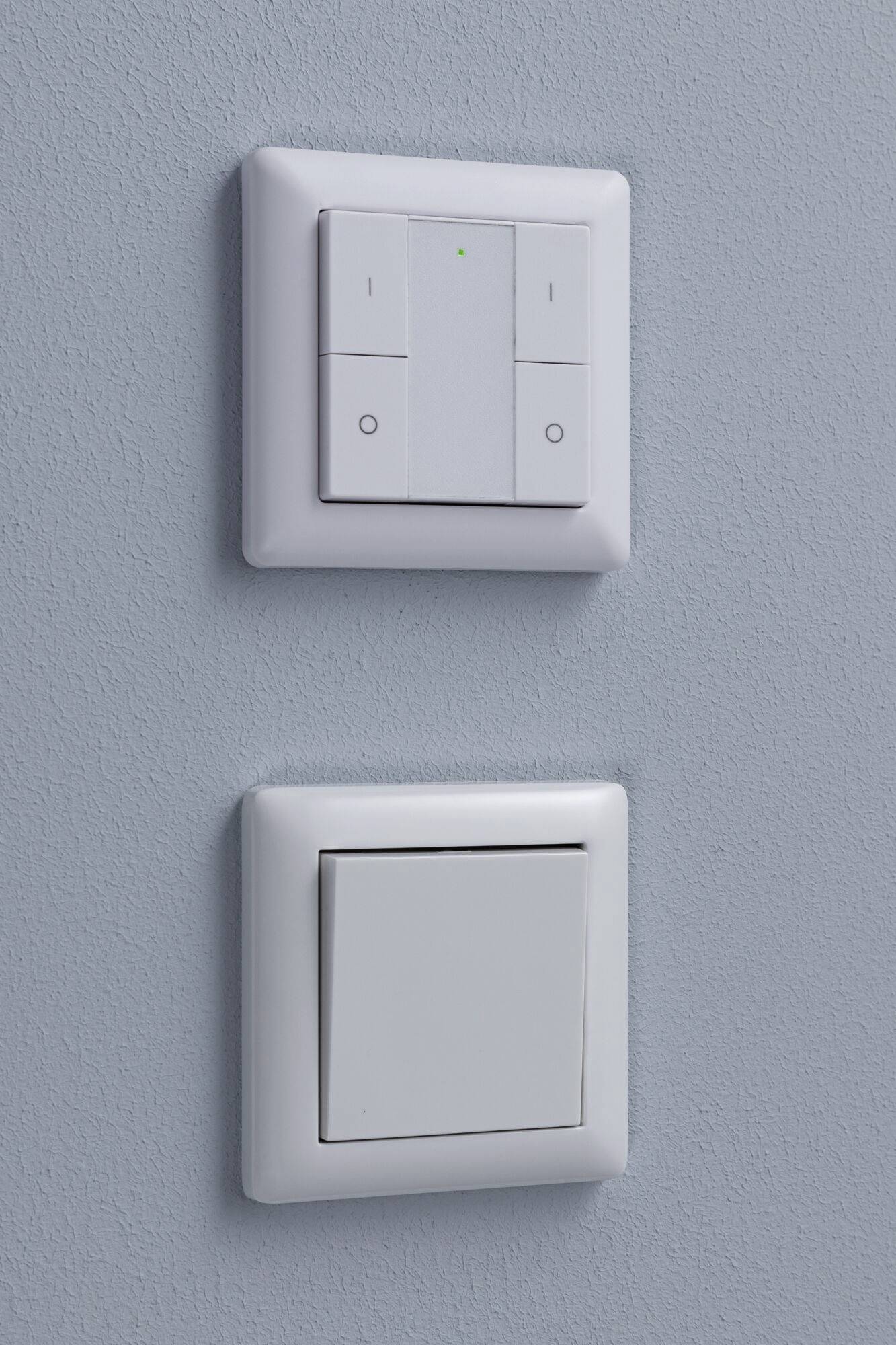 Light switch on a blue wall, consisting of a double switch at the top and a single switch at the bottom.