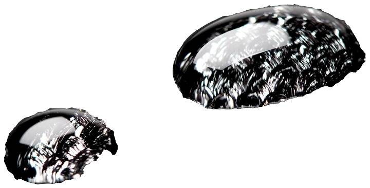 Two macroscopic water droplets on a smooth surface, displaying different light reflections.