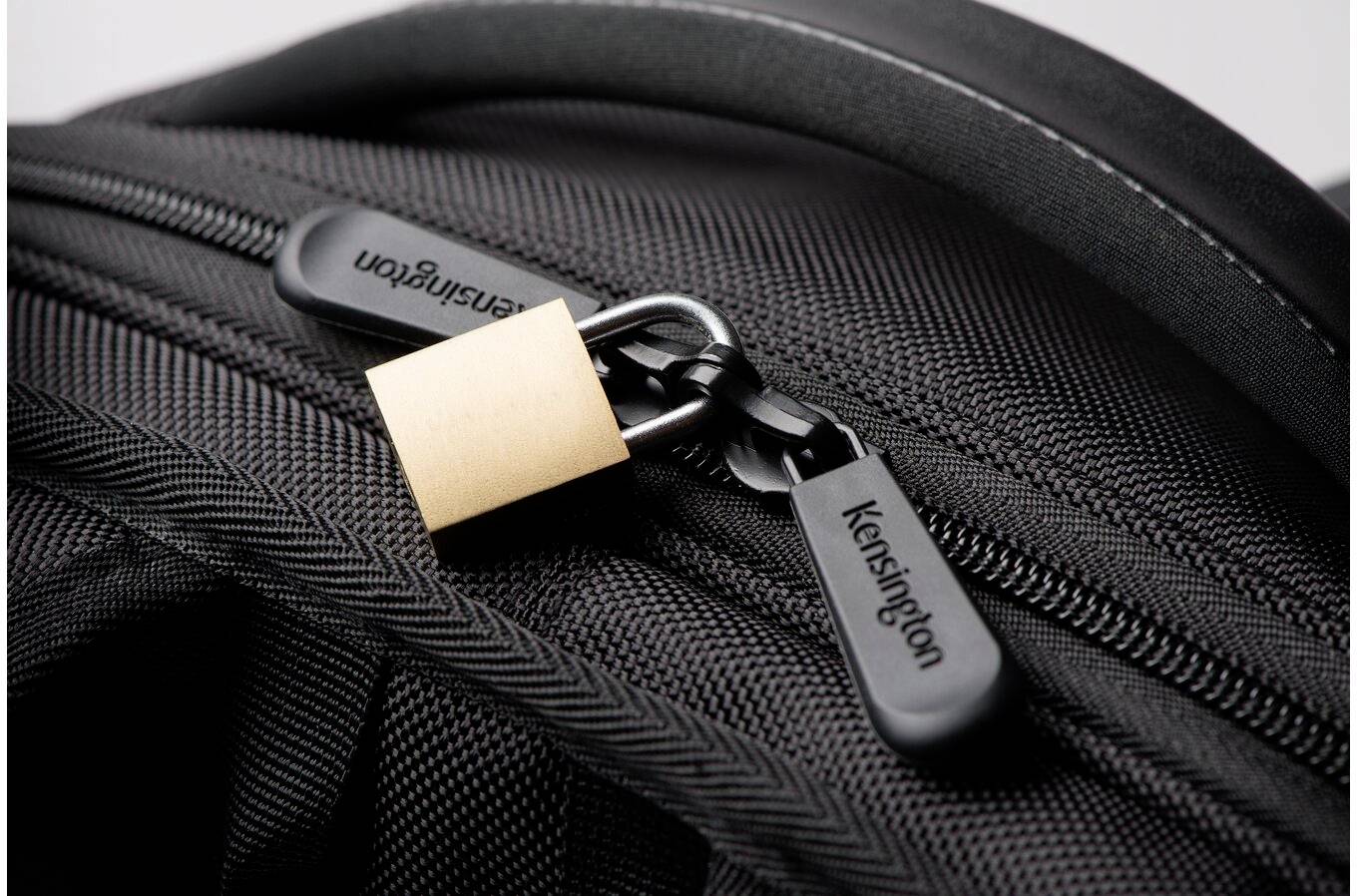 Black rucksack with two zips, secured by a small, golden padlock. 'Kensington' brand visible.
