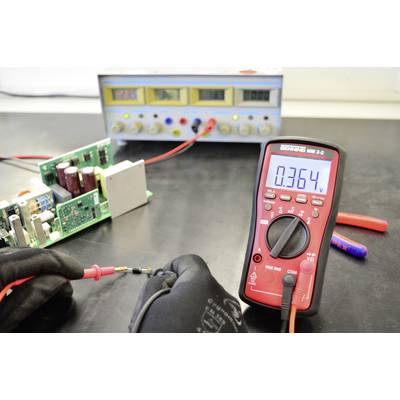 'A multimeter shows 0.364 V, next to an open device. In the background, a power supply unit and various electrical components.'