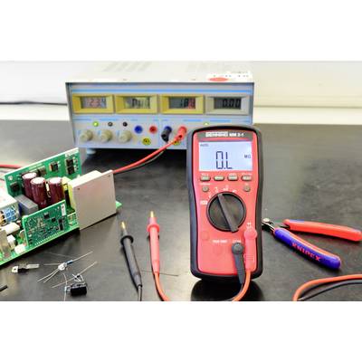 A digital multimeter shows zero ohms, alongside electronic components and a power supply with an illuminated display.