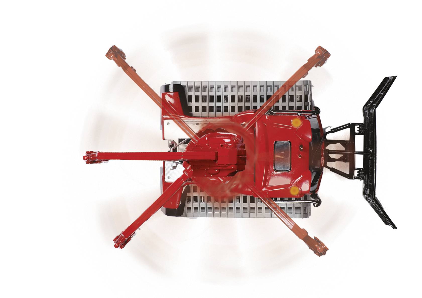 Red lawnmower viewed from above, with rotating blades. The mower has two visible handles and a black ventilation cover at the rear.