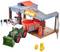 Toy farm with tractor, barn, cows and hay bales. The tractor is parked in front of the barn, with cows in the stable area.