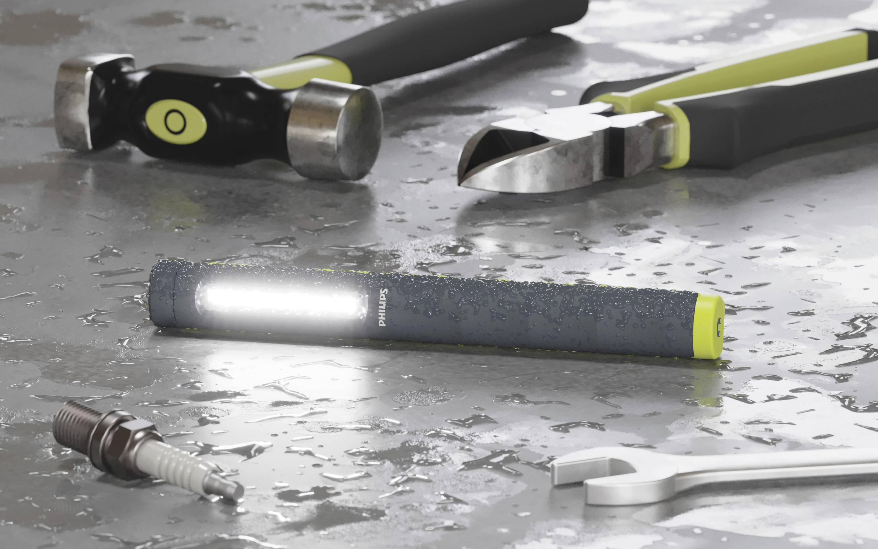 A bright torch rests on a wet, metallic surface, surrounded by various tools such as a hammer, pliers, and spanner.