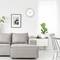 Bright living room with a grey sofa, wall clock showing 10:10, plants and artwork as decoration, creating a calm and modern atmosphere.