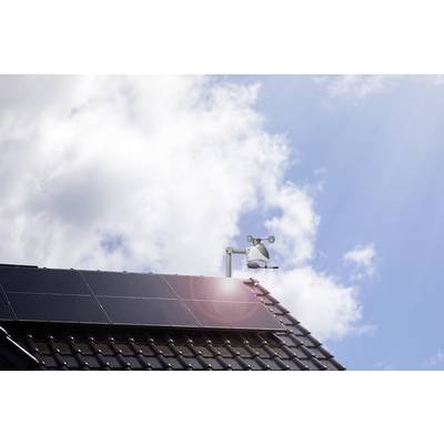Solar roof with a clear sky in the background. Solar panels on a pitched roof, with a weather station and wind gauge beside it.