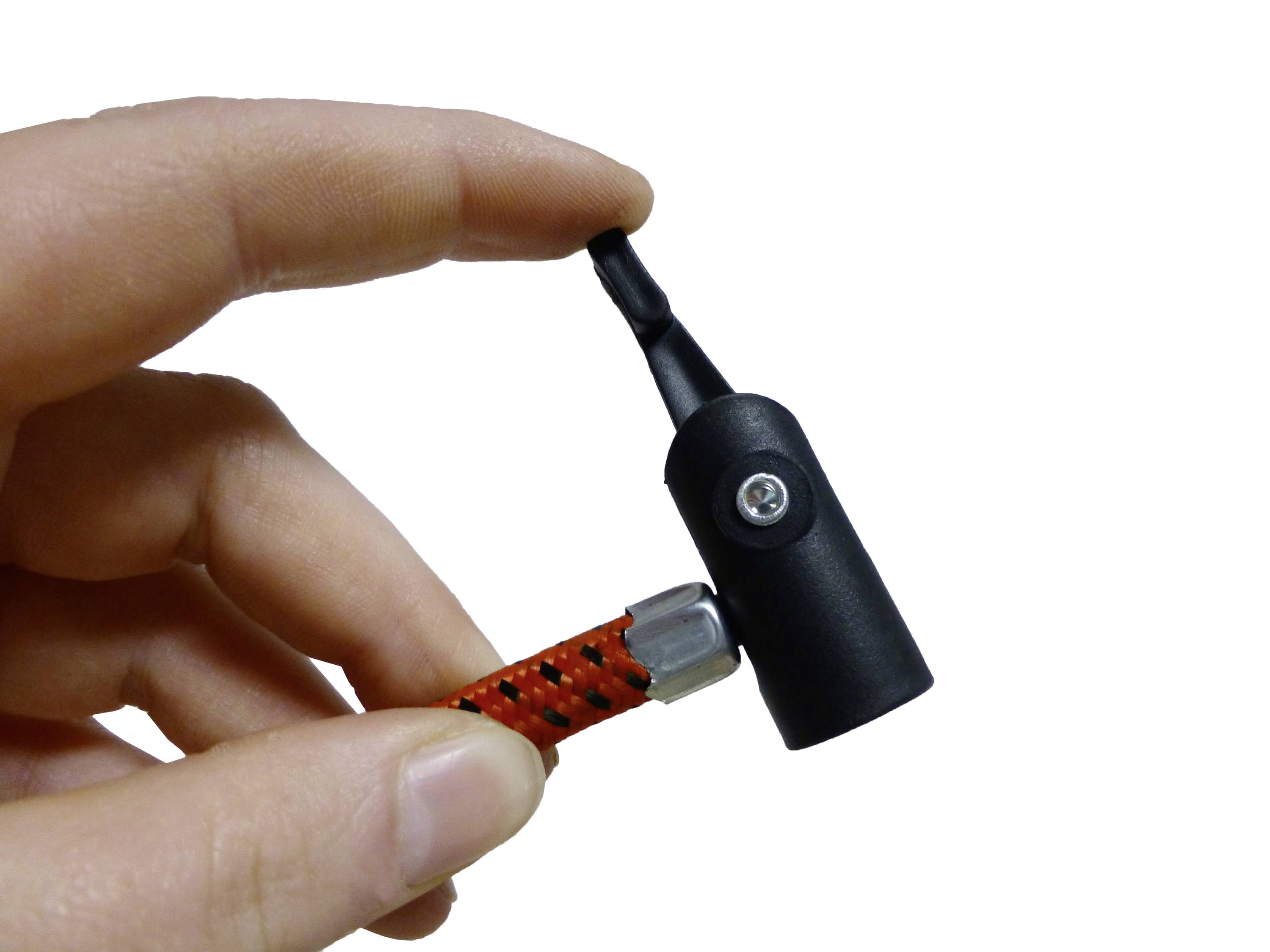 'Fingers are holding a small black cylinder with a screw connection.'