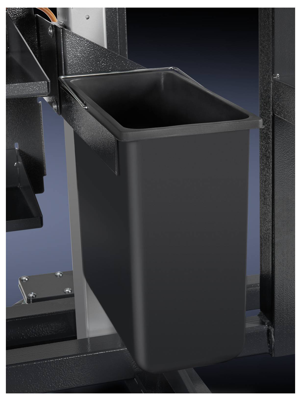 A rectangular, black container hangs from a metal frame, which is part of a larger machine structure.