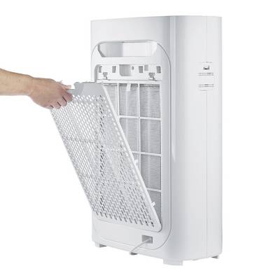 A person is removing the filter from a white air purifier. The device is standing upright while the filter is being taken out for cleaning.