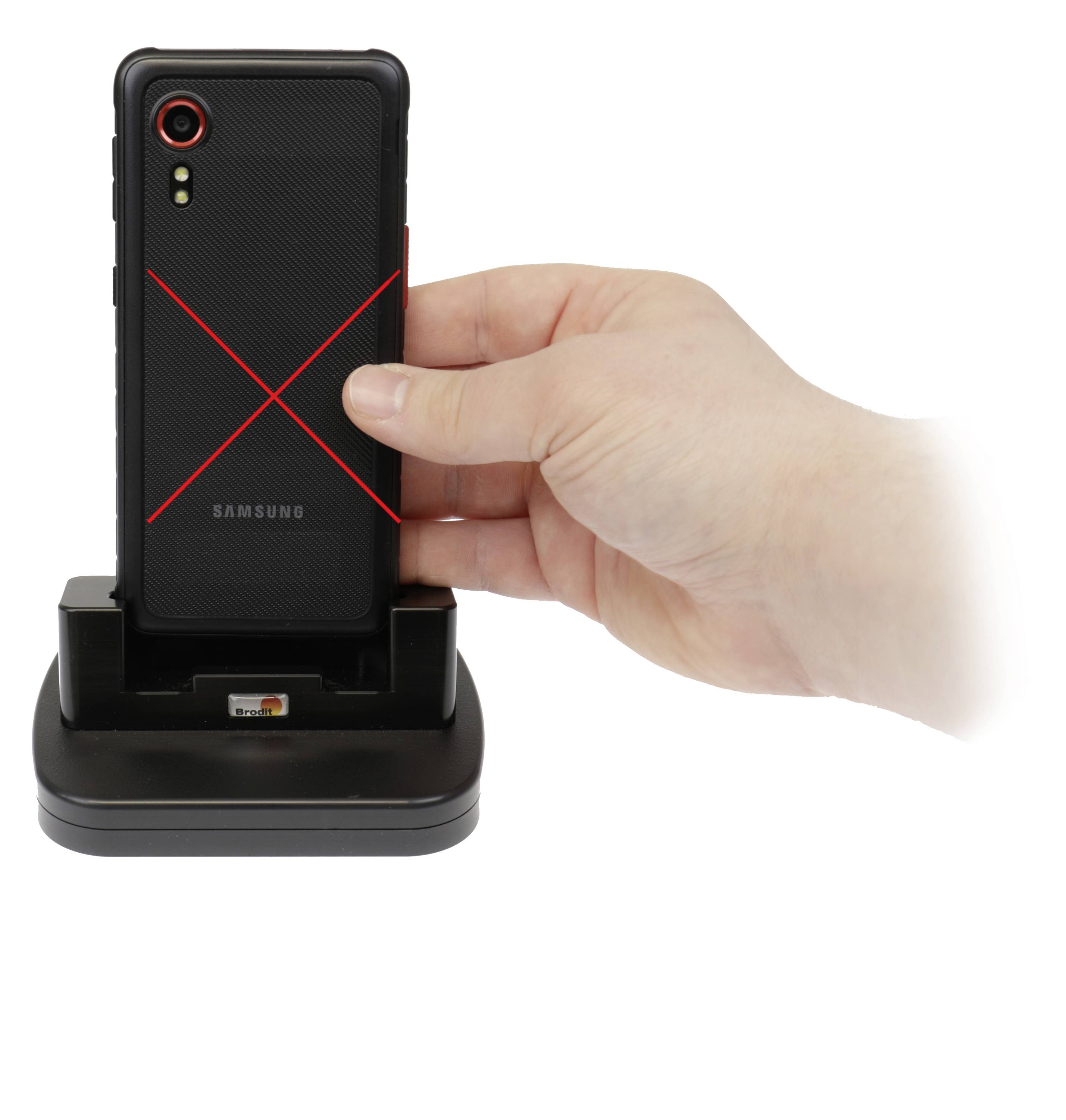 A hand holds a black smartphone with a red X pattern over a black charging station. The smartphone shows its back.