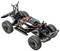 A black RC car chassis with tyres and visible electronics. Cables and battery are recognisable, without bodywork.
