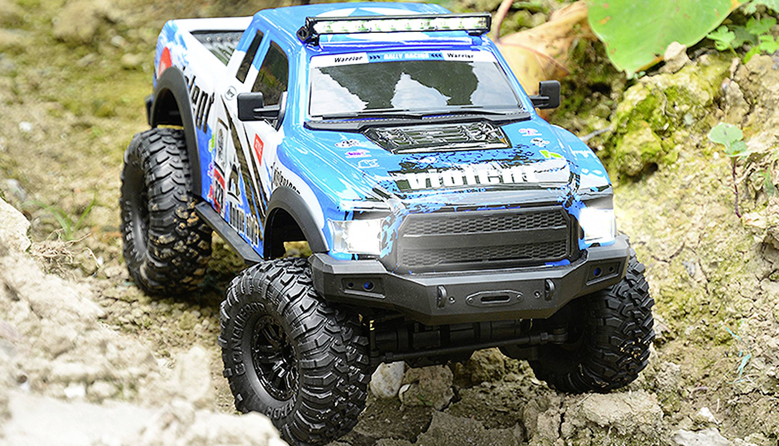A remote-controlled car traversing rough, rocky terrain, painted blue and white.