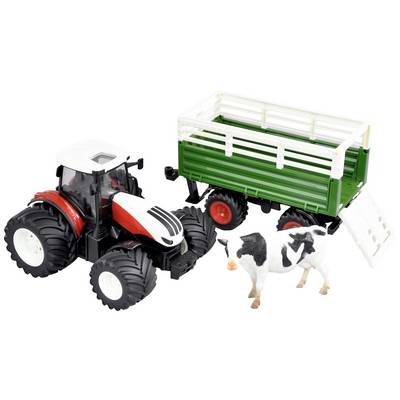 A toy tractor with a trailer next to a cow figurine. The tractor is red and white, the trailer is green, and the cow is black and white.