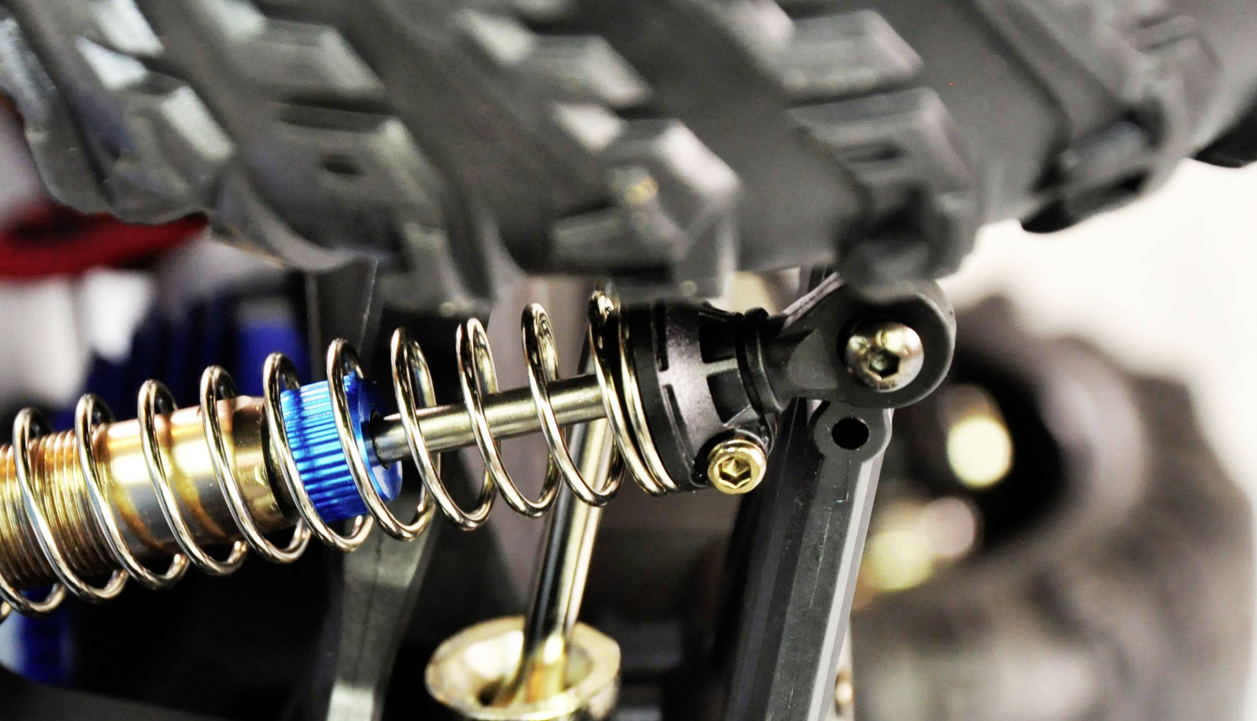 Close-up of a shock absorber with spring and bolt on a vehicle wheel with a coarse tread pattern. Technical or vehicle design in focus.