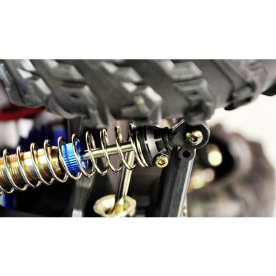 Close-up of a shock absorber with spring and bolt on a vehicle wheel with a coarse tread pattern. Technical or vehicle design in focus.