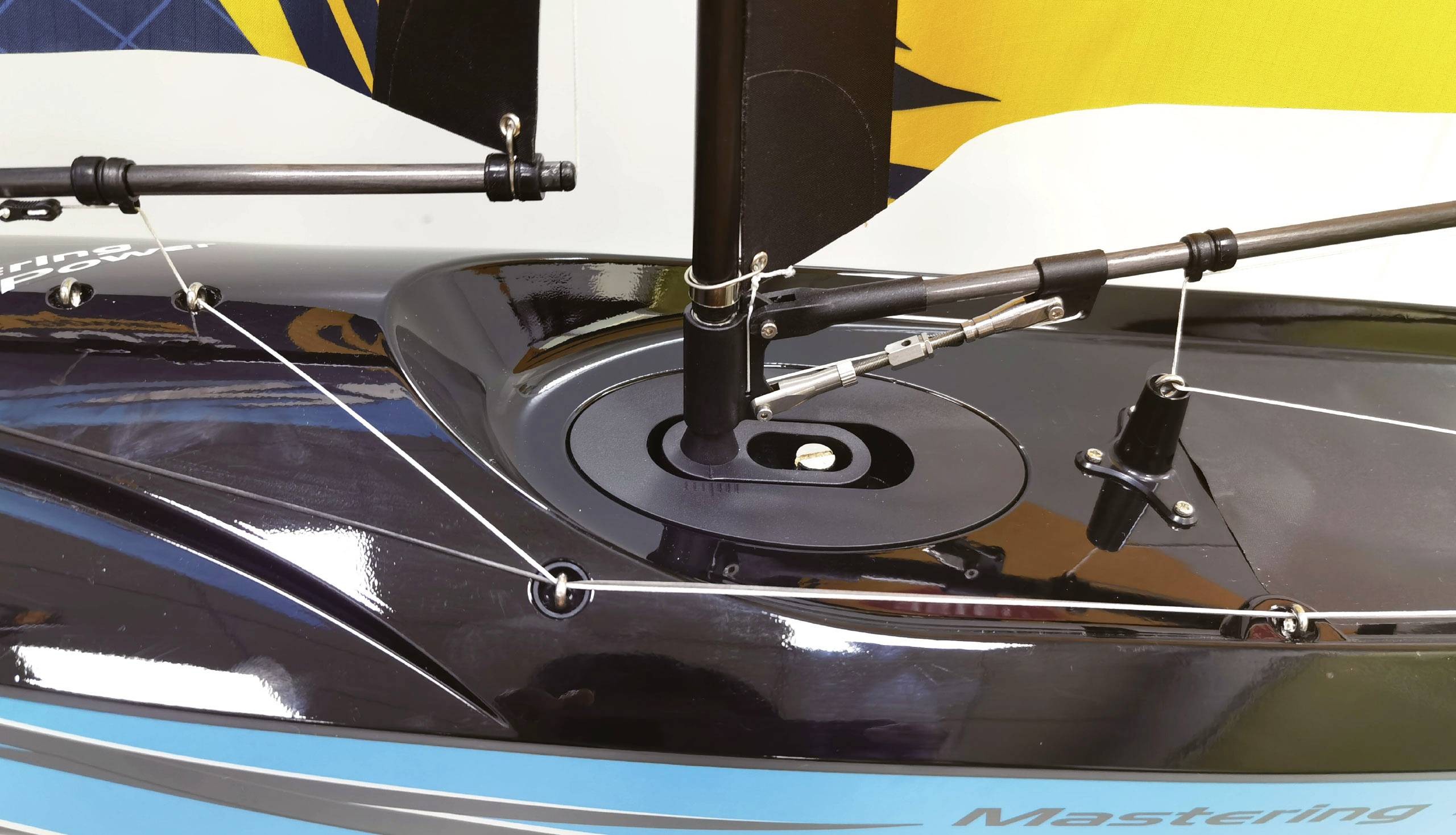 Model sailing boat deck with complex rigging and cordage detailed, including mast connections and control lines.