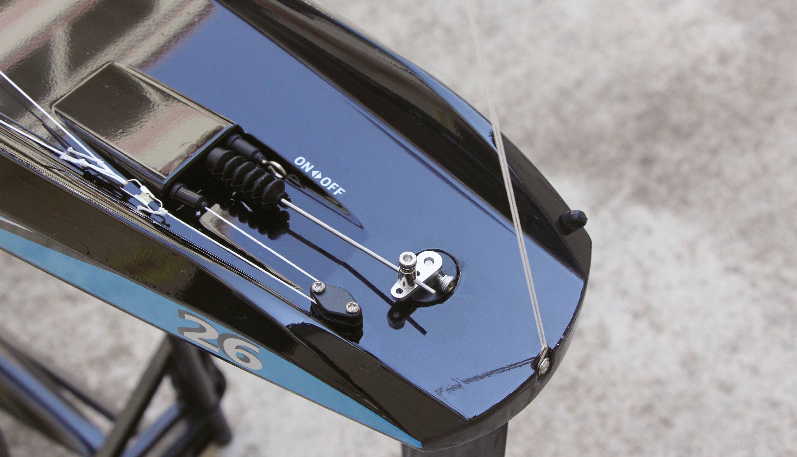 Close-up of a model boat with the number '26'. The boat has a glossy black surface with blue accents.