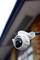 Security camera in close-up on a building wall, looking downwards. Surrounded by a blurred background.