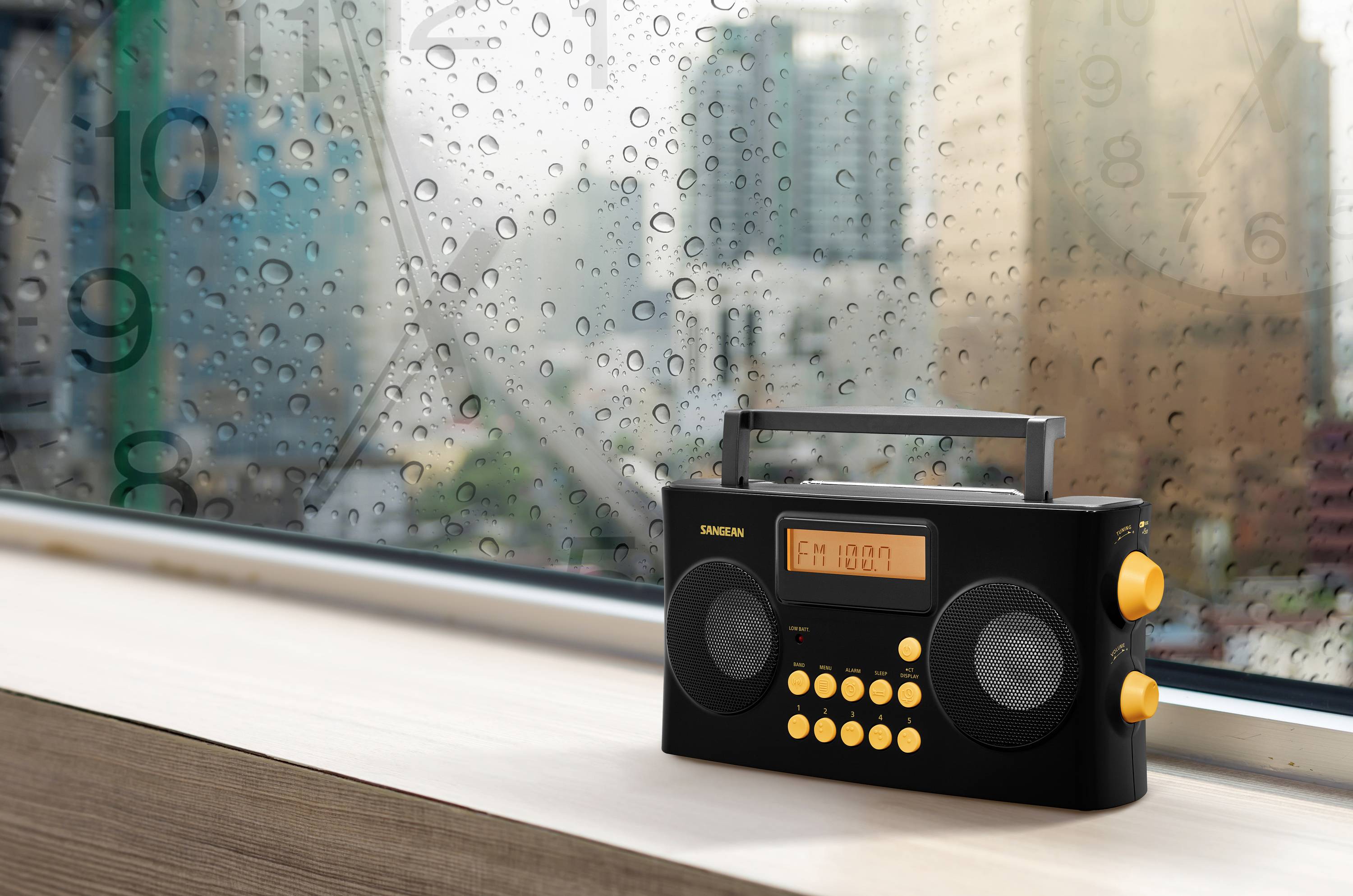 A black radio with yellow buttons sits on a windowsill. In the background, a rain-soaked urban landscape can be seen.