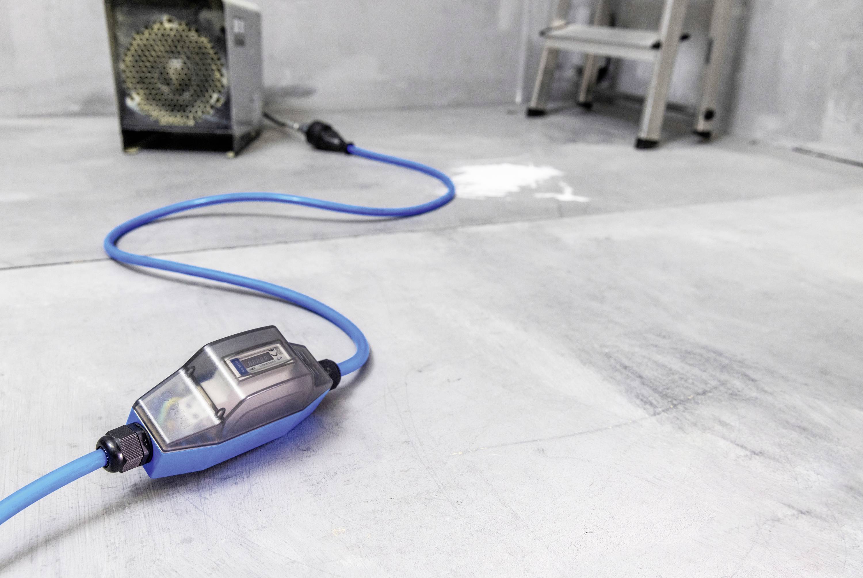 A blue high-voltage extension lead is lying on a concrete floor. An electrical device and a ladder are visible in the background.