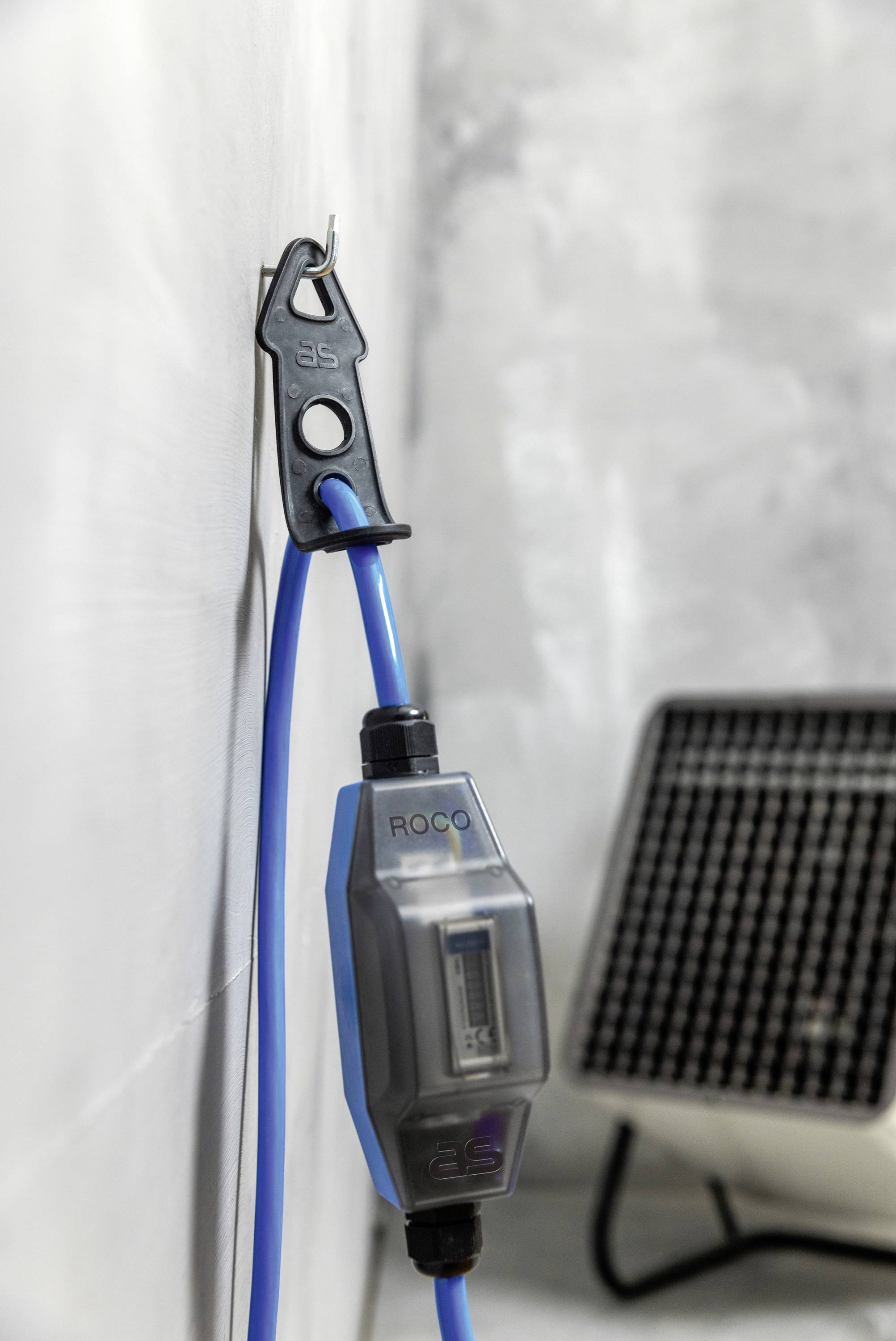 A blue Ethernet cable on the wall with a metre, next to an electric heater.