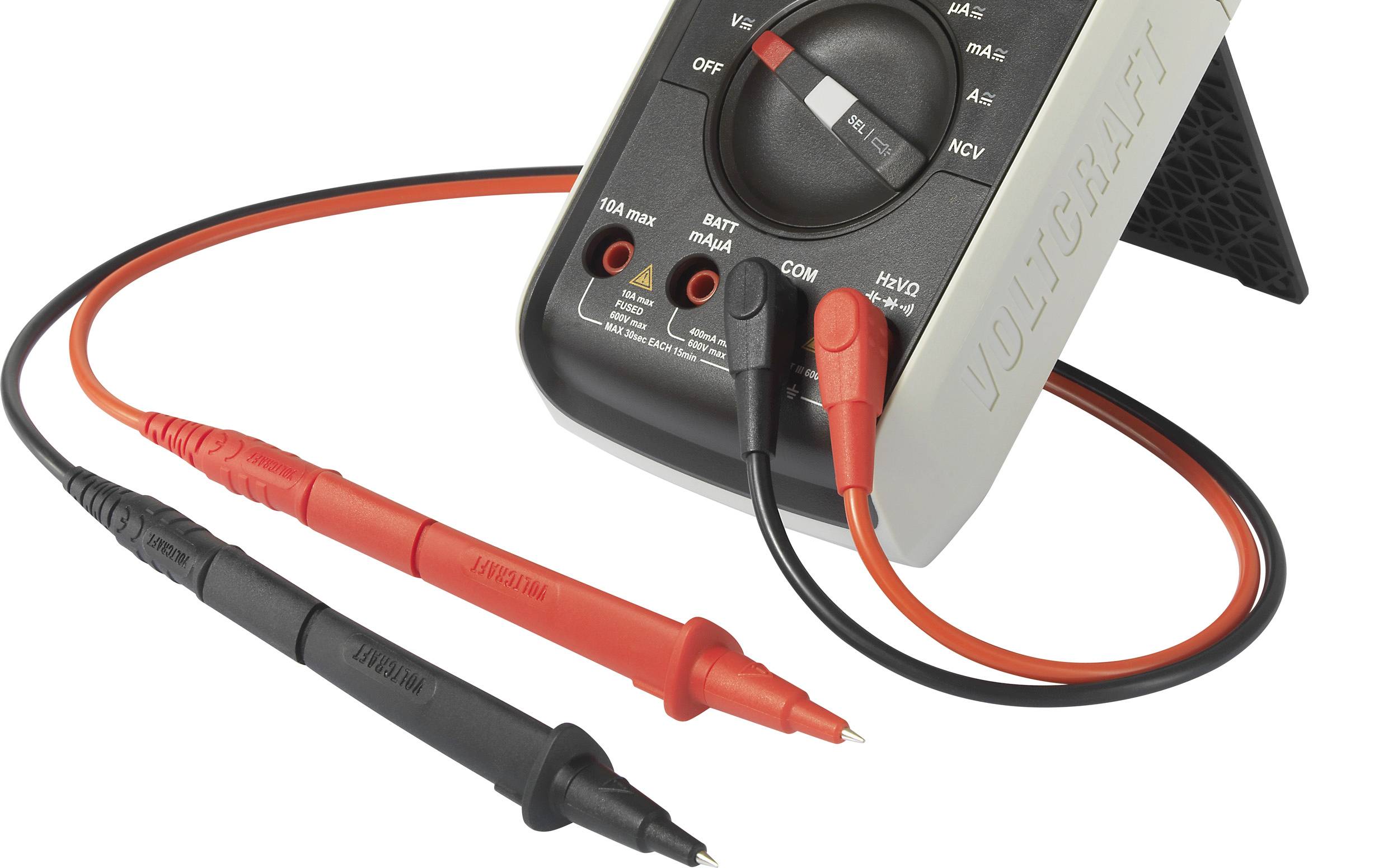 Digital multimeter with red and black test leads, tilted on a stand. Displays settings for voltage and current.