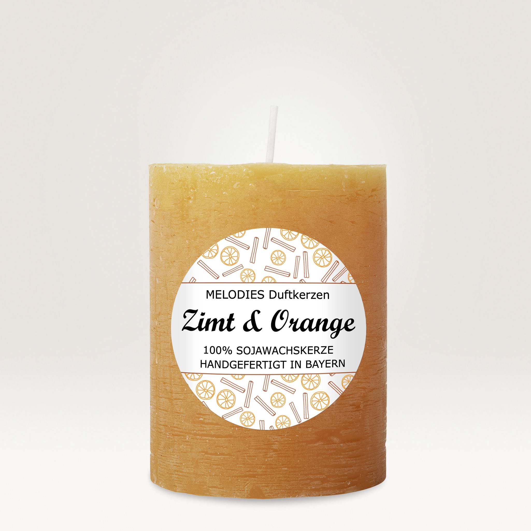An orange-coloured scented candle with a label. Text reads: 'Cinnamon & Orange', handmade from soy wax in Bavaria.